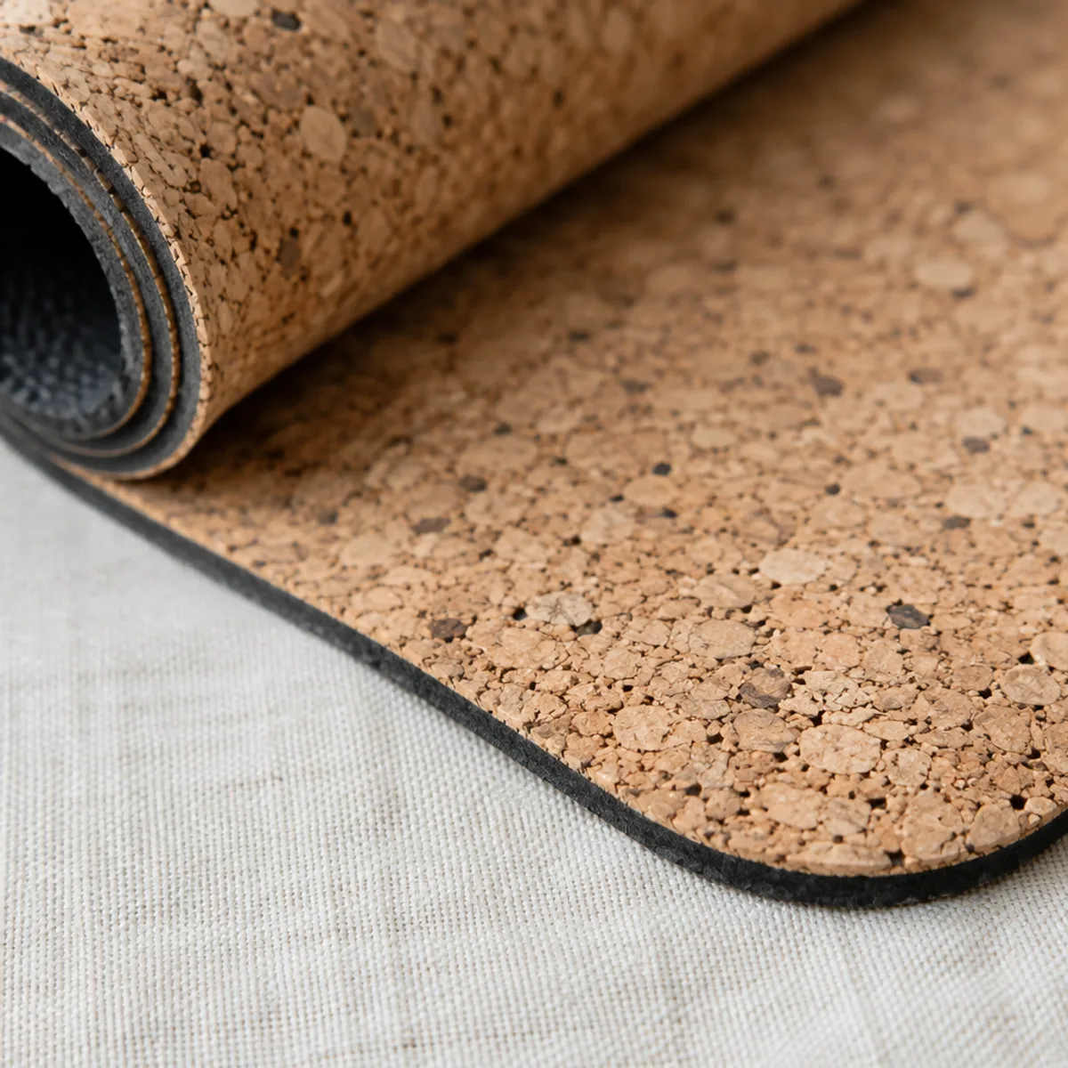Close-up of speckled natural cork texture on a yoga mat and the edge of its dark rubber base